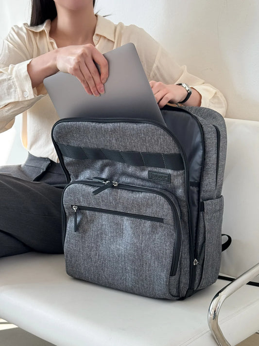 Person placing laptop in grey Bebefit backpack on chair, bebefit.eu, ergonomic design