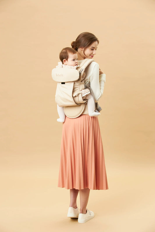 Mother carrying baby in beige bebefit.eu ergonomic baby carrier, modern neutral background