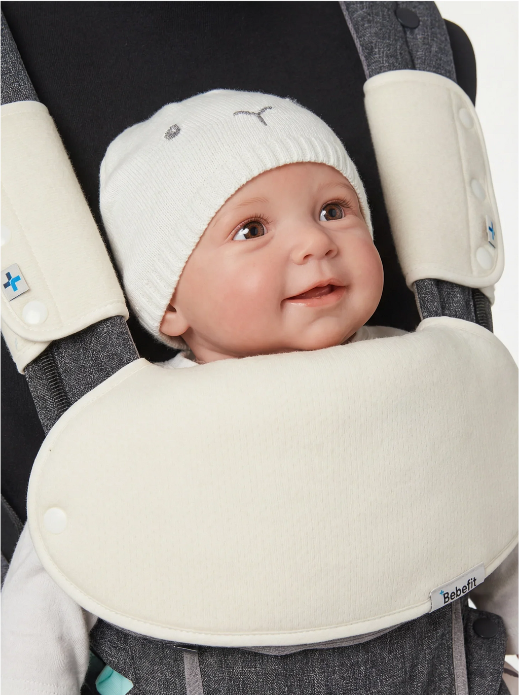 Smiling baby in ergonomic baby carrier with soft cream padding, bebefit.eu, baby carrier